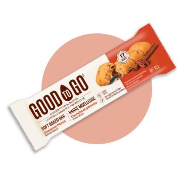 An individually wrapped GOOD TO GO Cinnamon Pecan Soft Baked Bar on a circular orange background.